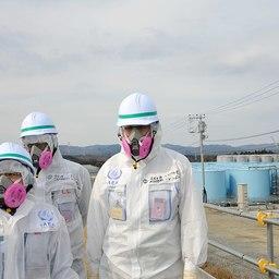 Представители МАГАТЭ на фоне резервуаров с загрязненной водой АЭС «Фукусима-1». Фото IAEA Imagebank («Википедия»)